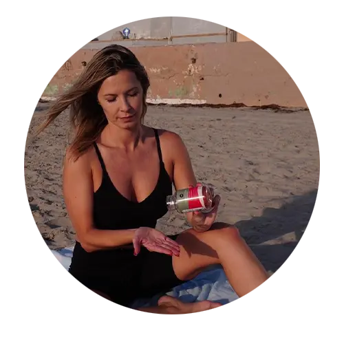 a women with blonde hair wearing a black dress popping out gummies from vegan collagen gummies with beach as the backdrop.
